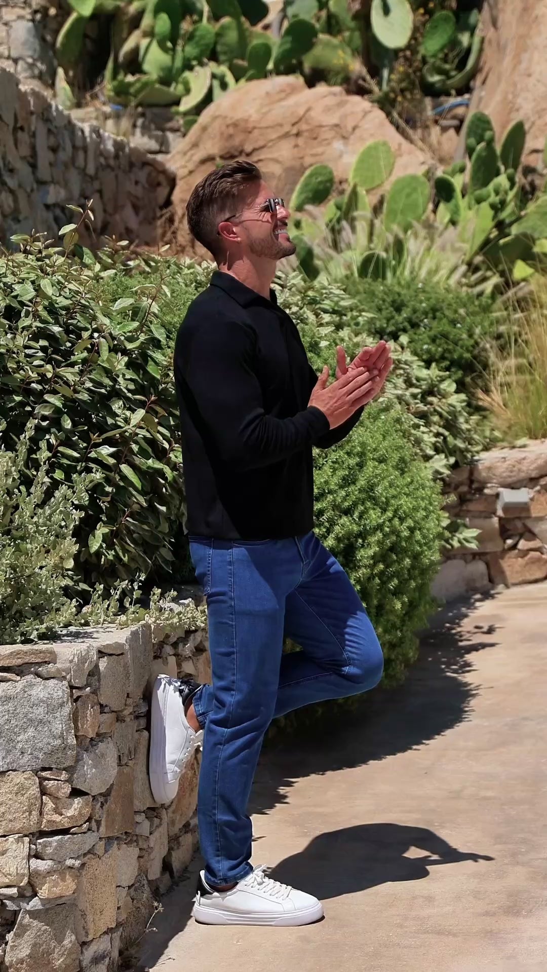 Man wearing long sleeve black open collar polo shirt with blue straight leg stretch jeans with classy style 