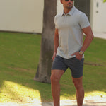 Man wearing athletic fit polo and dark grey slim fit chino shorts for stylish smart casual summer outfit by Kojo Fit