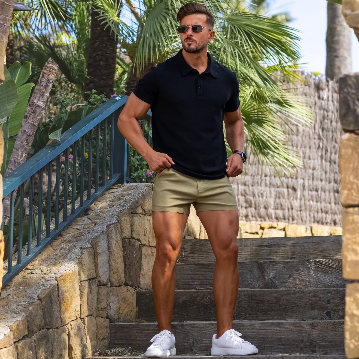 Man wearing black slim fit polo shirt with shorter length khaki casual shorts stylish summer outfit that shows off legs