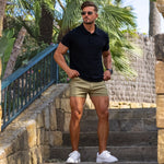 Man wearing black slim fit polo shirt with shorter length khaki casual shorts stylish summer outfit that shows off legs