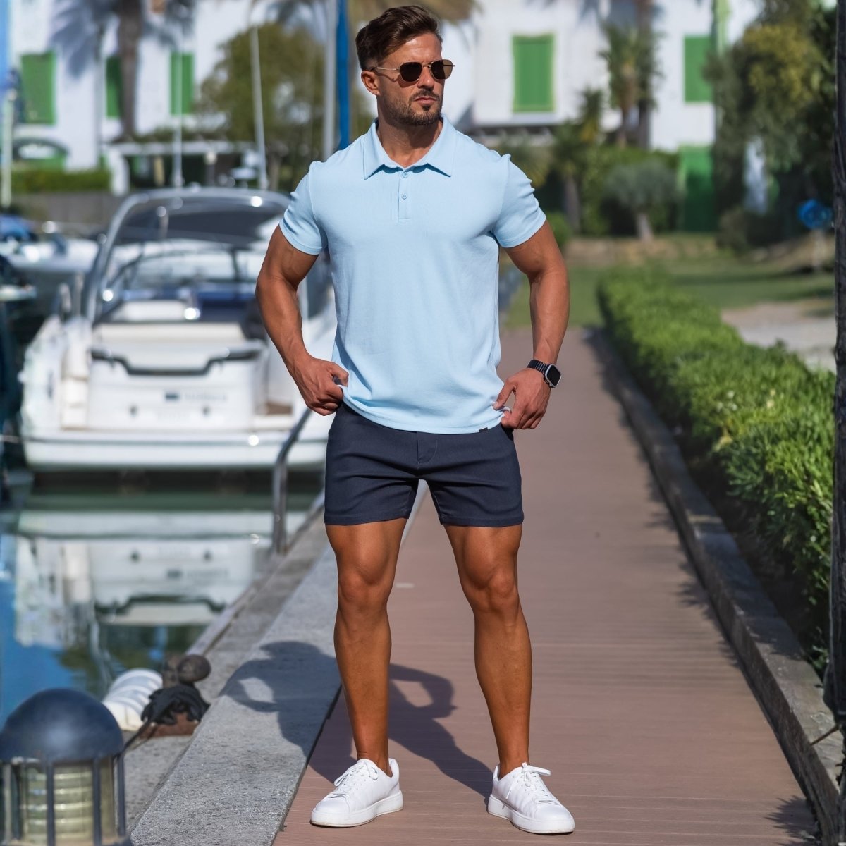 Man wearing Sky blue athletic fit polo shirt with short length casual shorts in dark grey for summer style by Kojo Fit