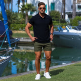 Man wearing black muscle fit polo with stylish shorter length mens chino shorts in olive green