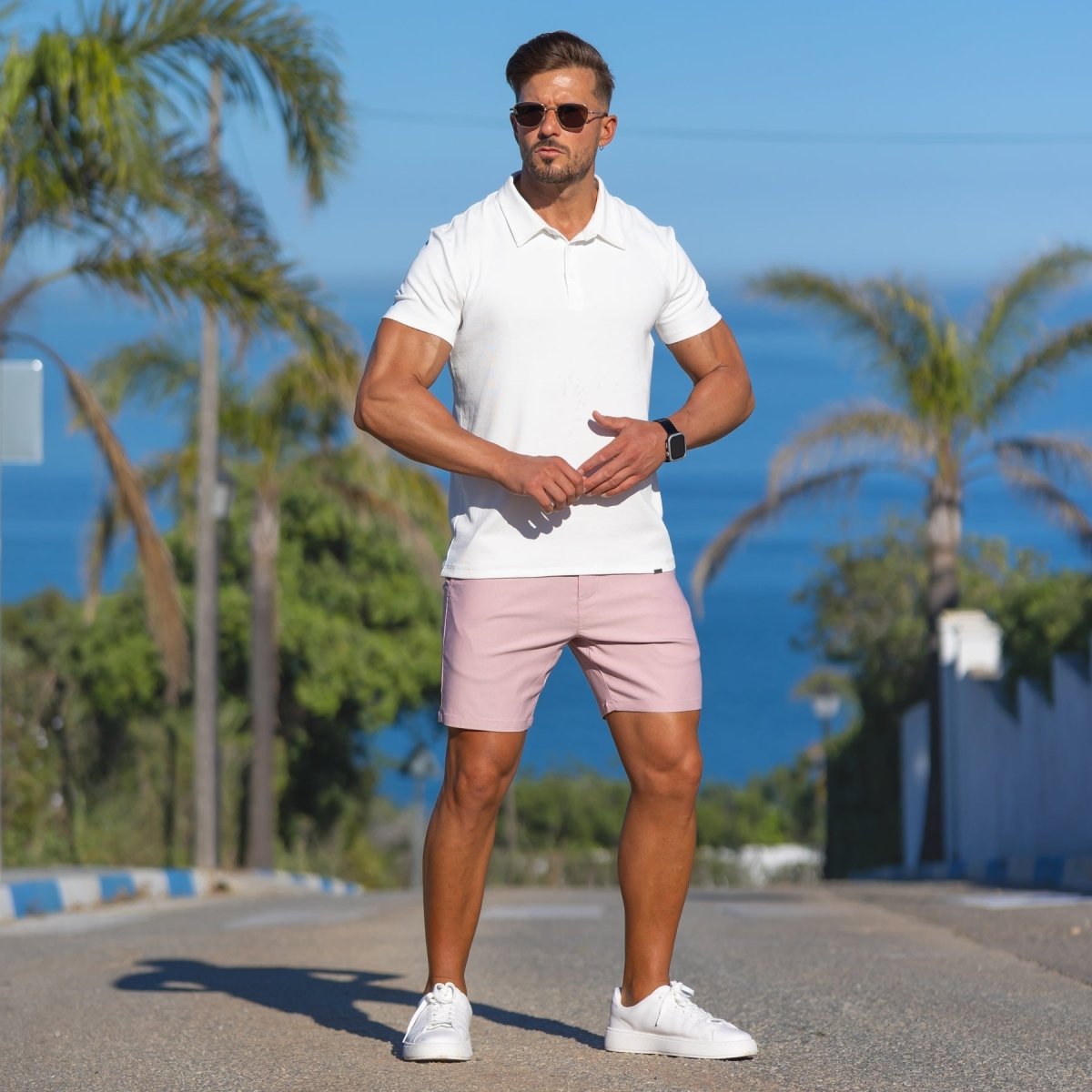 Stylish man wearing white classic knit polo and dusk pink casual slim fit shorts